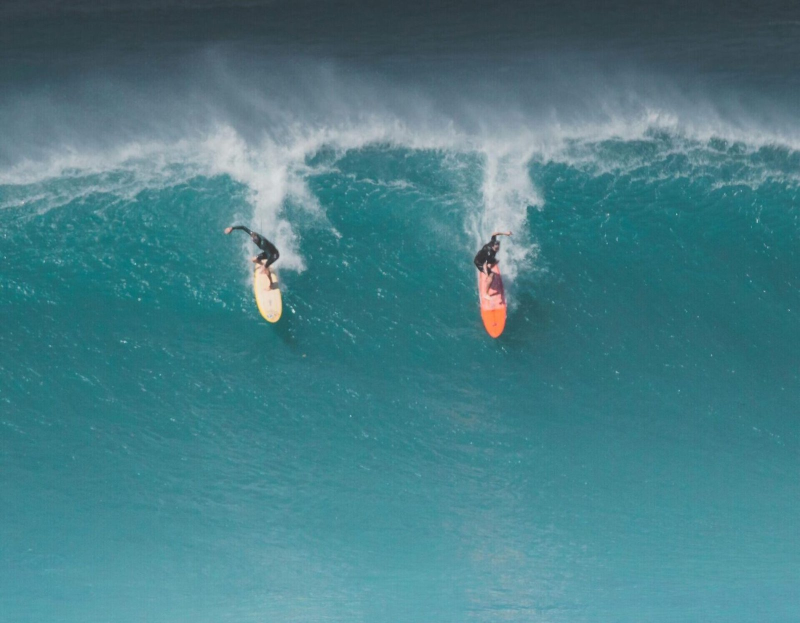 Two surfers ride massive waves in Hawaii, capturing the thrill of ocean sports.